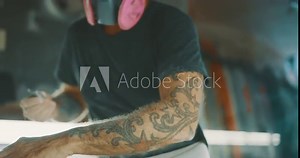 Surfboard shaper using a planer tool to shape a surfboard stringer, skilled craftsman working with his hands shaping a new surfboard