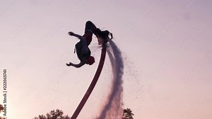 Flyboarder doing flip tricks slow motion flying Flyboarding medium shot video on sunset backlight
