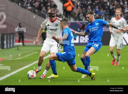 31 January 2026, Hesse, Frankfurt/M.: Soccer: Bundesliga, Eintracht Frankfurt - Bayer Leverkusen, Matchday 20, Deutsche Bank Park. Alejandro Grimaldo (M, Bayer 04 Leverkusen) and Aleix Garcia (r, Bayer 04 Leverkusen) pressurize Rasmus Kristensen (l, Eintracht Frankfurt). Photo: Marc Schüler/dpa - IMPORTANT NOTE: In accordance with the regulations of the DFL German Football League and the DFB German Football Association, it is prohibited to utilize or have utilized photographs taken in the stadiu