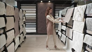 decor and design, happy female customer buys goods for apartment renovation in a hardware store, woman chooses new wallpaper to decorate a room on background of shelves with paperhanging