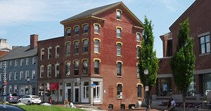 A daytime summer exterior establishing shot of red brick buildings and businesses along Fore Street in downtown Portland, Maine.
