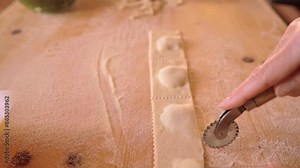 4k slow motion close-up view following the hands cutting the strip of filled pasta to make green tortelli or vegetable ravioli. Traditional italian vegetarian or vegan recipe