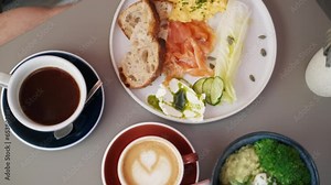 Healthy brunch in the city. Close up of full breakfast, bowl salad with broccoli, avocado. Plate with eggs, salmon and bread, coffee and cappuccino Stock Video