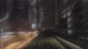 Time lapse. A ride inside of an overground train through multiple stops of the financial district at night.