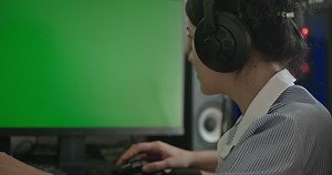 Young Woman Playing Game on Desktop PC Computer Green Screen Monitor. Gamer Sit at Desk Table 4K 10 bit