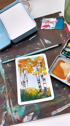 Andrea Nelson on Instagram: "Postcards are back in the shop! Supplies are my brand and are on my page https://www.adreamoradayart.com/ Painting a simple fall landscape is super easy when you use an old gift card to make the trunks of the trees! Add some fall leaves and some scratchy ground cover and sky, and you have a beautiful little landscape! 24 color essential palette Watercolor postcard Size 6 round brush Artist tape Old gift card Posca colored pencils are on my Amazon page https://www.ama