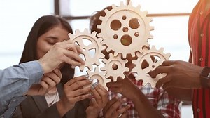 Office worker holding cog wheel as unity and teamwork in corporate workplace concept.