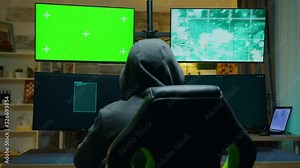 Back view of hacker wearing a hoodie using computer
