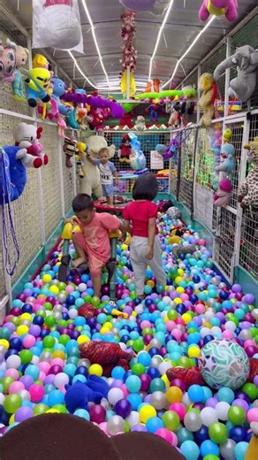 My brother is playing on the yellow slide in the ball pool.