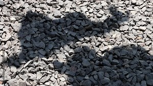 The Abstract shadows move on a small stones. The waving shadows of the drying laundry swing on the ground with rocks, slow motion.