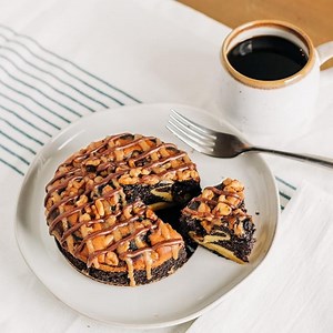 Infused with aged Kentucky Bourbon, topped with fresh walnuts, and drizzled with chocolate and caramel, the ORIGINAL Kentucky Woods® Bourbon Barrel Cake makes a delicious, unforgettable treat. 🍰🥃 Ships free in a unique bourbon barrel across the continental United States! | Adam Matthews Cheesecake