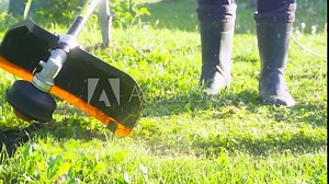 worker mows green grass on the lawn with hand trimmer. lawn care. weed control. Woman with gasoline mower cutting grass. Grass trimmer worker, garden work.