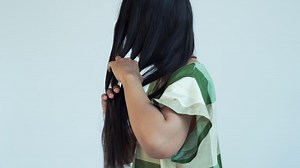 a woman combing her hair with both hands facing sideways