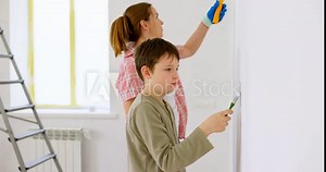 Happy family mother and son paint the wall with paint using roller and brush
