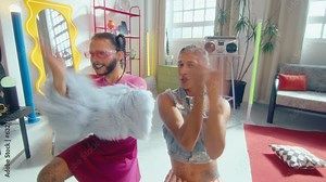 Artistic LGBTQ couple of cross-dressed guy and his gender fluid partner in y2k outfit performing energetic vogue dance, smiling and posing for camera in trendy designed studio. Zoom shot Stock Video