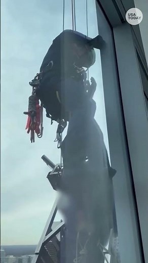 Watch crews scale high-rise to free workers stuck on titled platform