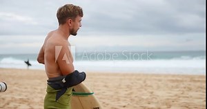 Professional surfer wearing a wetsuit on banzai pipeline north shore Oahu Hawaii. preparing to surf on a beach.