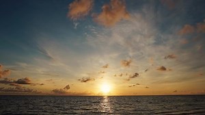 Time lapse sunrise beach Australia. Clouds fast in the sky. Time-lapse of fast flying clouds in the sky. The big sun rises from behind the clouds.