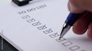 Close-up businessman tick off or marking with blue pen on checklist, checkbox, to do list box after completing task on white paper. Selective focus 4K resolution. Checklist and To Do List Concept