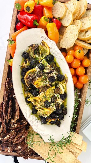 Turkey can wait. This warm feta and olive dip using Pearls All-Natural Ripe Olives by Chef Jamie Gwen is the real reason we gather early. 🫒✨ Ingredients: 8 ounces feta cheese, 1 can Pearls All-Natural Ripe Olives, drained pitted olives, 4 garlic cloves, peeled and smashed, 1/2 lemon, thinly sliced, 1 teaspoon sumac, 1 teaspoon roasted garlic powder, 1/2 teaspoon ground black pepper, 1/3 cup extra virgin olive oil, 1 tablespoon freshly chopped herbs of your choice, Honey, for drizzling, Bread, c