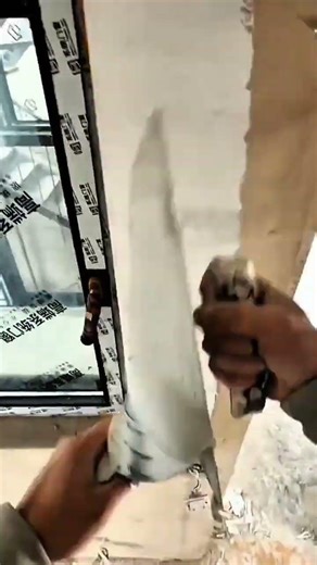 Hand applying plaster smoothly around window frame