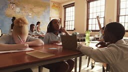 Slow motion shot of teacher crouching near desk with students...