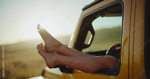 Relaxing on epic road trip, close up of feet hanging out the window of the car at sunset