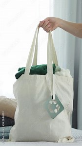 Keep a textile bag made of recycled material filled with things, clothes for recycling. Donate clothes for reuse. The recycling symbol on the labels.