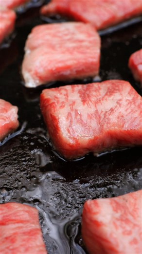 Tender Wagyu beef cubes seared over open fire, stacked in crispy rice cakes. Celebrating rich flavors. #WagyuBeef #OutdoorCooking #SimplePreparation #Cooking | Cook Loop
