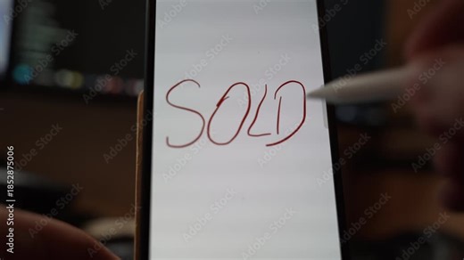 Close view of the word SOLD handwritten with a stylus on a smartphone screen signaling completed transaction and sales outcome through digital note taking in an indoor setting