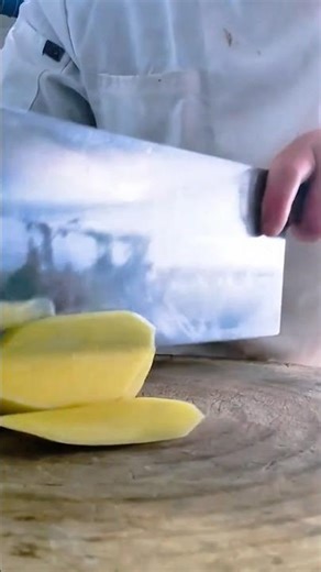 Chef using large metal cleaver to slice yellow potatoes