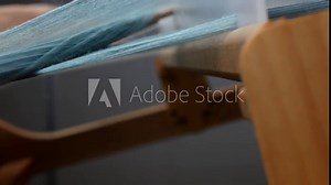 Process of weaving side view, close up. Shuttle is carrying the crosswise threads through the lengthwise threads. Loom details