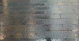 Raindrops and commuter footsteps on the rainy sidewalk at night.