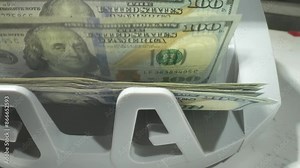 Money counting. Close up currency counting machine counting dollar bills. Machine counter calculates 100 dollars banknotes in slow motion. Closeup currency count machine counting dollar banknotes.