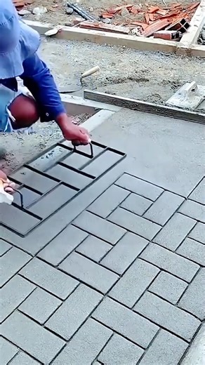 Worker stamping fresh concrete to create patterned brick design