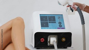 A dermatologist stands with equipment for laser hair removal. Cosmetologist adjusts device settings for laser hair removal procedure