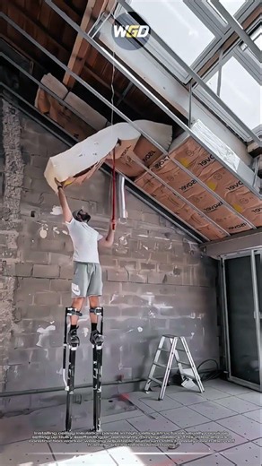 High ceiling insulation panels installation uses stilts to easily reach the roof framing