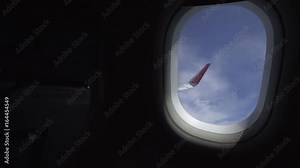 Airplane window view showing wing of the plane flying over land