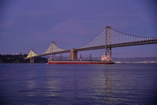 Behind the Bay Bridge lights: An artist, perched on a terrace, with a laptop