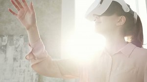 Caucasian girl watching 360 video at home, wearing VR headset. Pretty woman touch something using modern virtual reality glasses at home on a sunny day