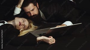 Business couple using laptop - addicted. Handsome man and pretty woman on black background - Social addicted. The workplace romance trick. Typing write message. Social media.