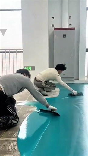 applying turquoise epoxy resin coating to a concrete floor using a professional metal squeegee tool
