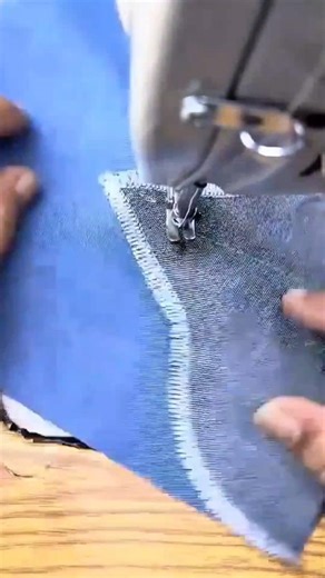 sewing a small triangular piece of grey fabric onto a blue textile using a professional machine