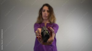Slow motion handling of large black handgun. Woman out of focus, gun in focus