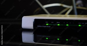 Wireless Home Router with blinking green led lights on reflective glass surface. Close up of PWR, SYS, WLAN leds.