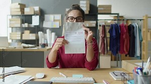 Woman speaking on camera and showing parcels while video calling during workday in delivery service office