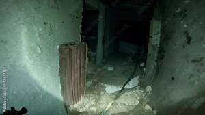 Man is exploring an abandoned building, using a flashlight to see in the dark