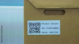 Hand of man using wireless barcode reader, reads information from a QR code on the box. The QR code does not contain any information.