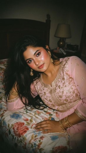 khushiii🌸 on Instagram: "No Need To Follow🎀 Prompt 2: convert the uploaded image into High-angle POV, medium close-up of a young South Asian woman with medium lenght messy brown hair, reclining on floral bedding. Intimate calm gaze, dewy makeup with pink blush and highlighter. Wearing dark peach & light peach transparent zari work embroidery work chiffon ethnic wear with long dupatta shimmering gold Zari work, jhumkas, and bangles. Hard on-camera flash lighting, deep vignette, dark bedroom bac