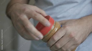 A man opens a jar of peanut butter.